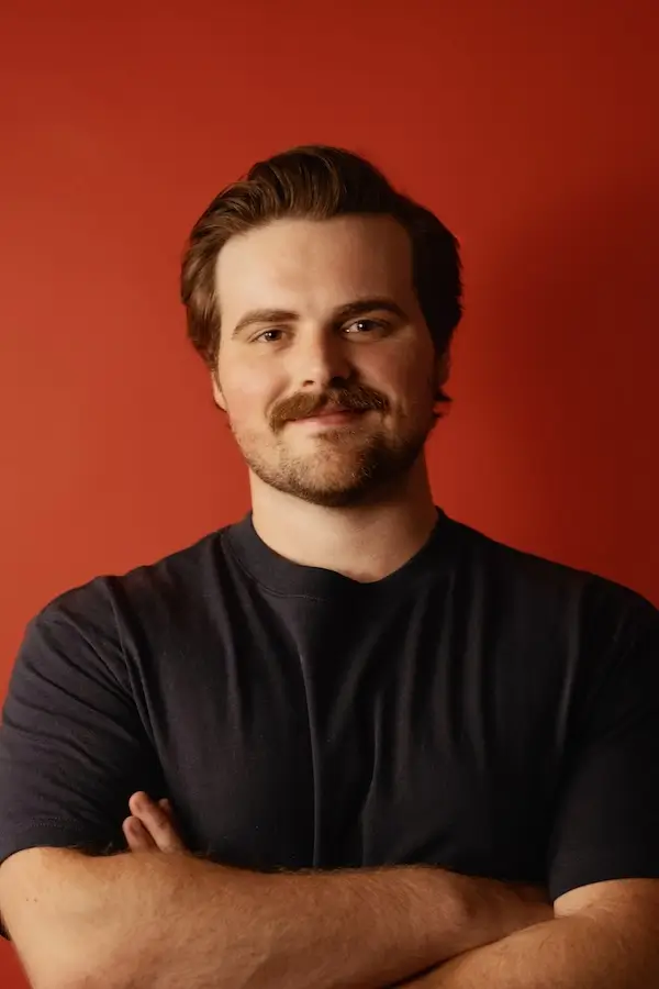 Portrait photo of Rare Breed Co. co-founder and Chief Executive Officer, Chandler Nigh, featuring a red background.